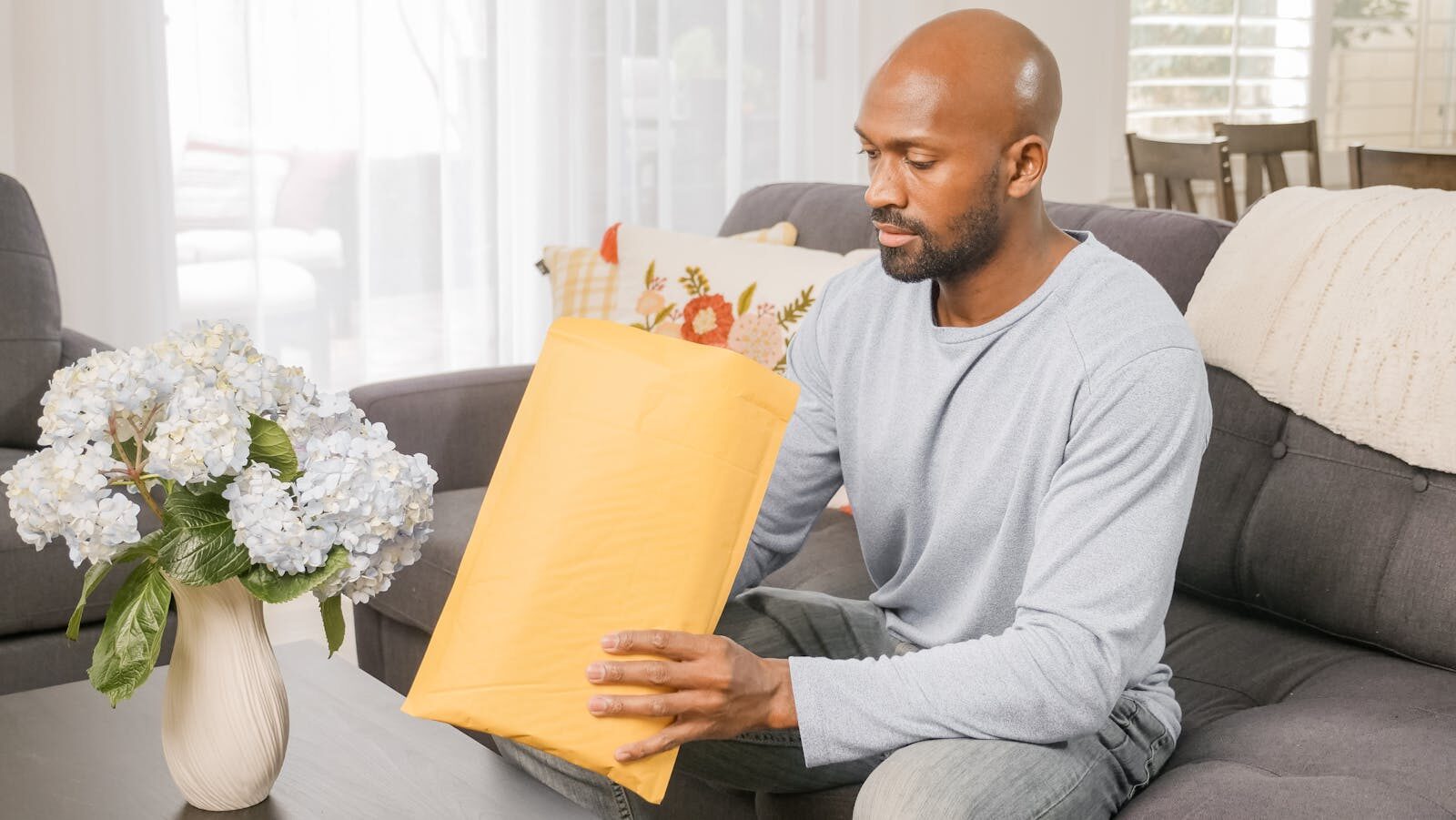 An adult man in a comfortable setting admiring a newly received package.