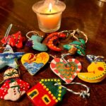 Handmade christmas ornaments and lit candle on table